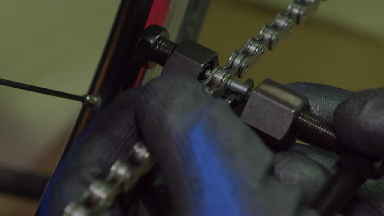 자전거 메카닉은 자전거 체인에 링크를 입하기 위해 도구를 사용합니다.