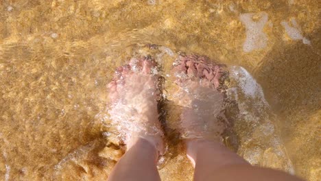 feet enjoying waves on sandy beach