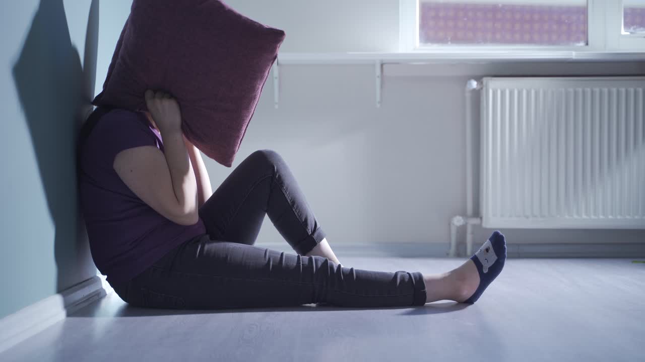 두려움으로 베개를 머리에 누르는 여자.