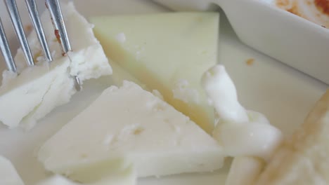 close up of a plate of feta cheese with a fork and knife