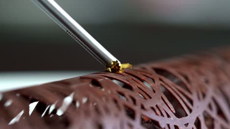 a person decorated a chocolate with a gold liquid, close up shot, insert shot