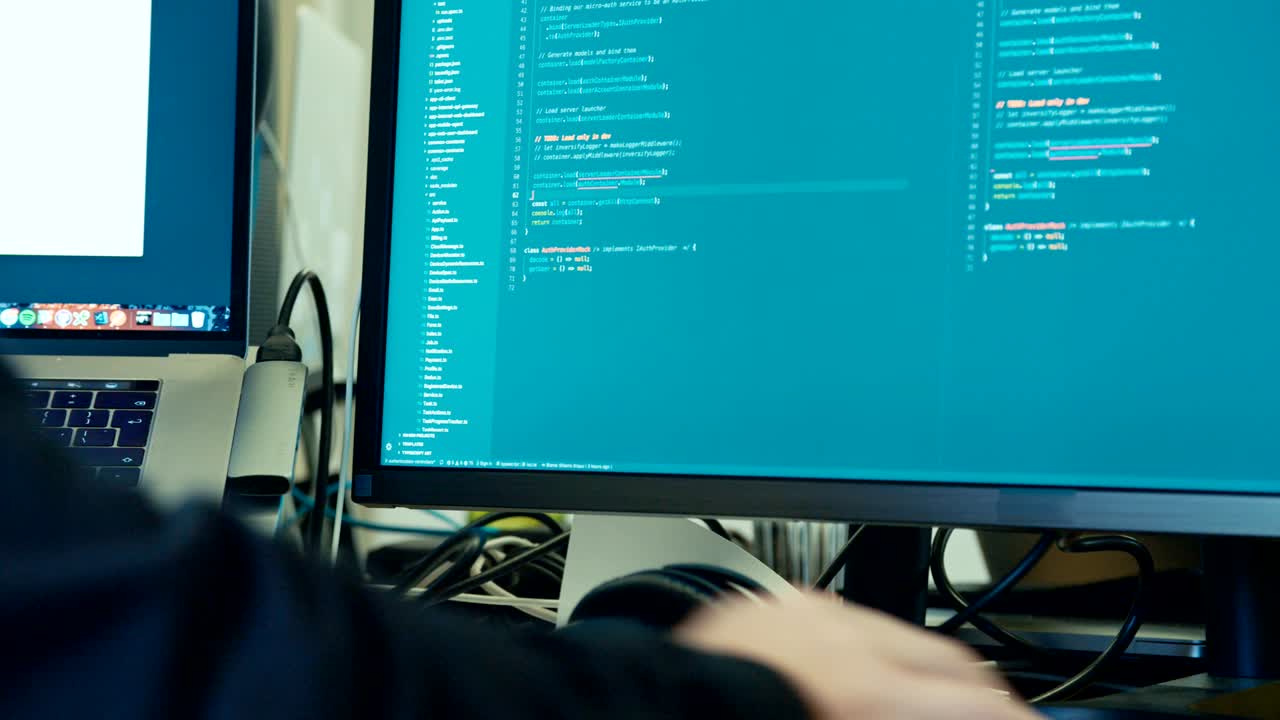 programador de computadora sentado frente a una pantalla codificando software