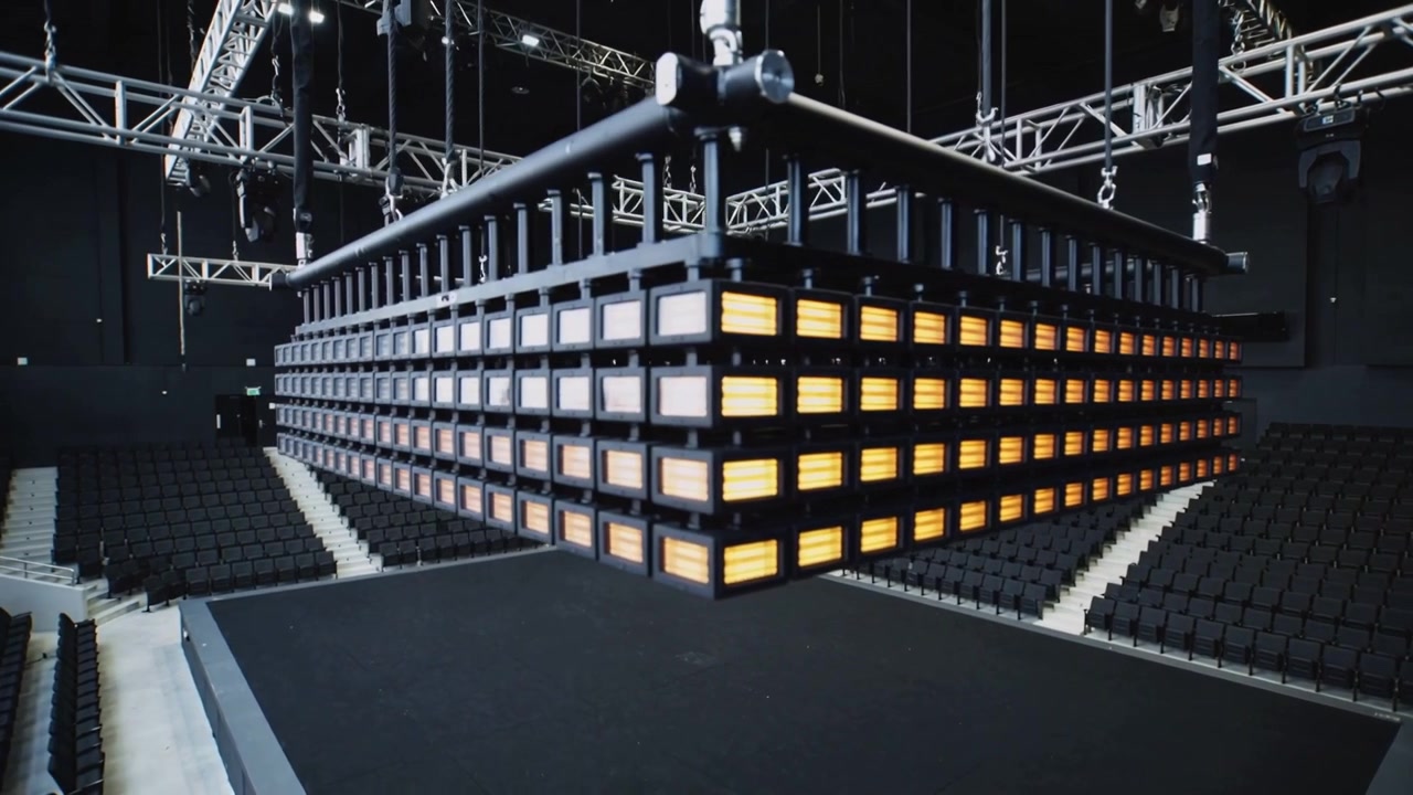 Illuminating suspended LED panel array responding to lighting cue, lowering over stage with truss