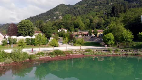 Vuelo-De-Drones-Cerca-De-Un-Bote-Pequeño-Que-Se-Refleja-En-El-Agua-Verde-Azulado-Del-Lago-Barcis-Dolomitas-Norte-De-Italia