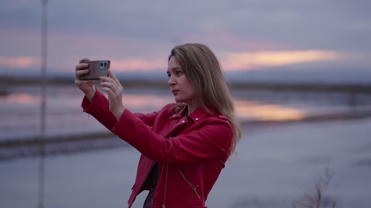 mujer tomando una selfie al atardecer junto a un lago