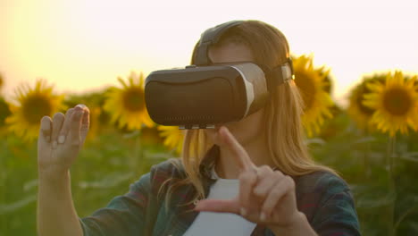 la joven está trabajando en gafas vr. está involucrada en el proceso de trabajo. es un día soleado perfecto en el campo de girasoles.