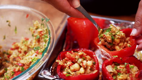 isolated view of red bell peppers being filled with tasty chickpea stuffing - slow motion