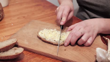 Woman's hands with salt, then cut a slice of bread smeared with butter and garlic on a chopping board