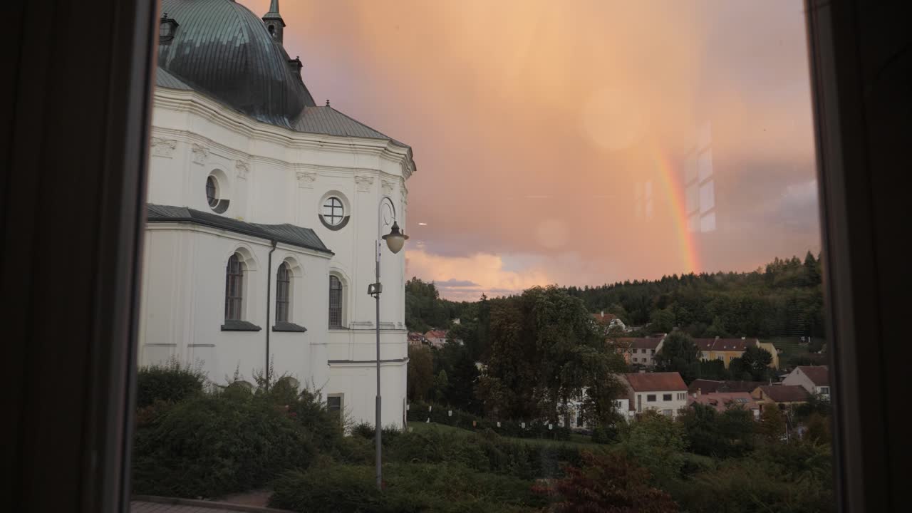 Křtiny church in sunset with rainbow through the window