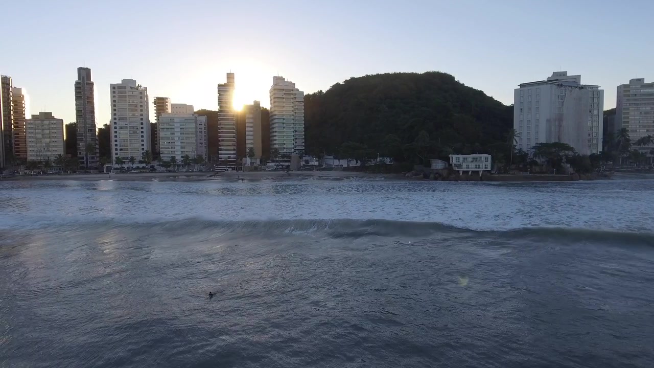 Laaja ilmakuva dronella Pitangueirasista, Guarujásta, Brasiliasta auringonlaskun aikaan. Turkoosit valtameren vedet kohtaavat rannikon tässä henkeäsalpaavassa ilmakuvaotoksessa.