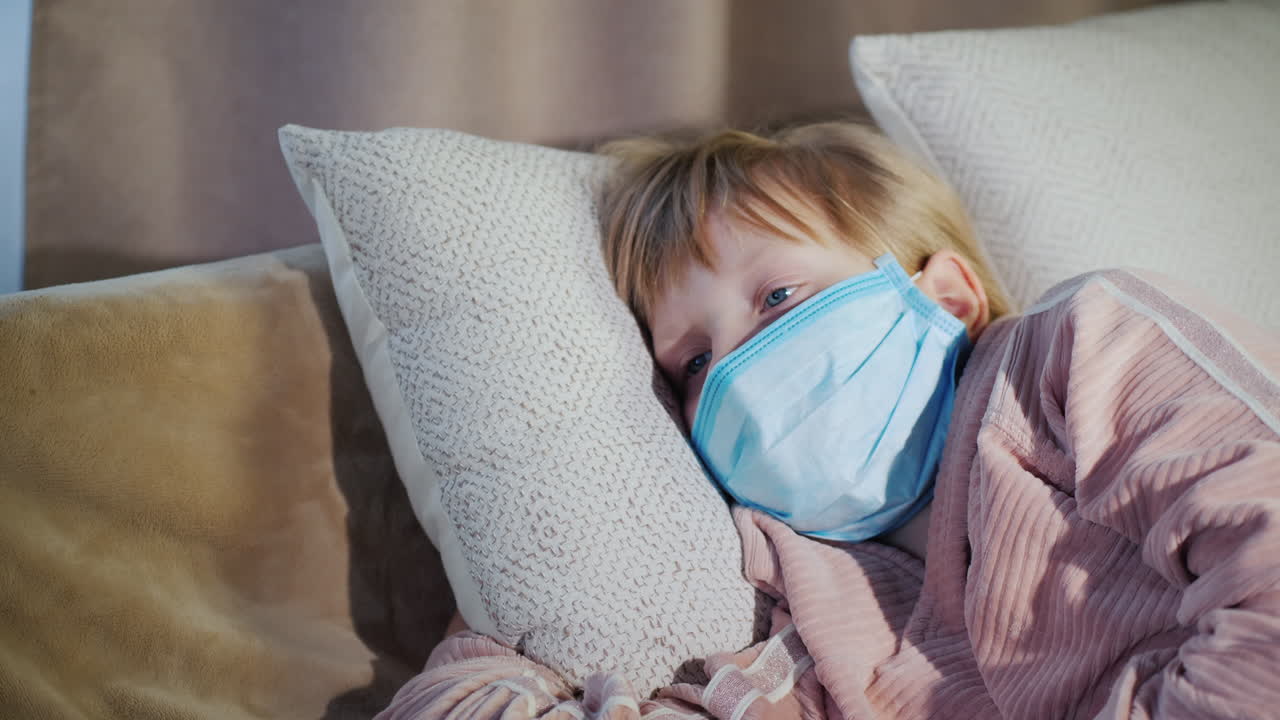 Sick Child Lies In Bed In A Gauze Mask