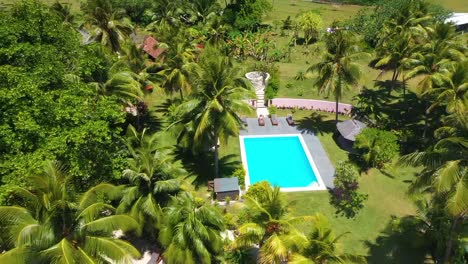 aerial pull back from a young tourist woman beside a hotel pool at a tourist resort on vanuatu pacific islands