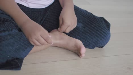child sitting on a wooden floor, focusing on hands and feet