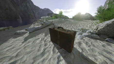 old suitcase on sandy shore mountains behind and sun shining