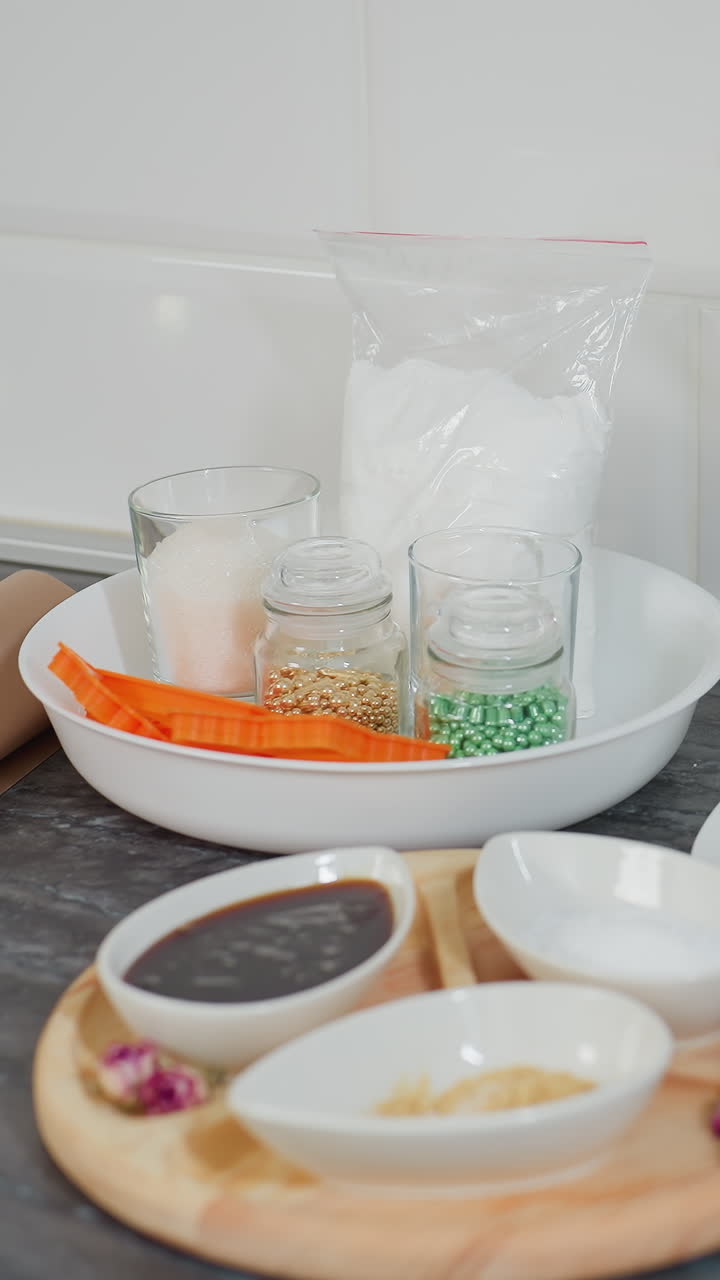 소스, 설탕 및 향신료로 가득 찬 세라 그, 접시에 버터, 유리 항아리, 쿠키 커터 및 전원 소켓에 베이킹 재료를 담은 나무 트레이가 있는 현대 주방 카운터