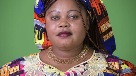 overweight beautiful african woman wearing traditional clothing against green background