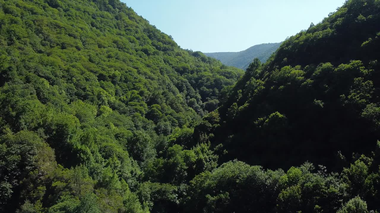 toma aérea, drone entre los dos lados de una montaña verde cubierta de árboles en asturias, españa