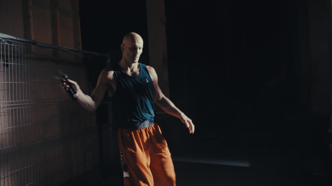 Uomo che salta la corda in una palestra buia