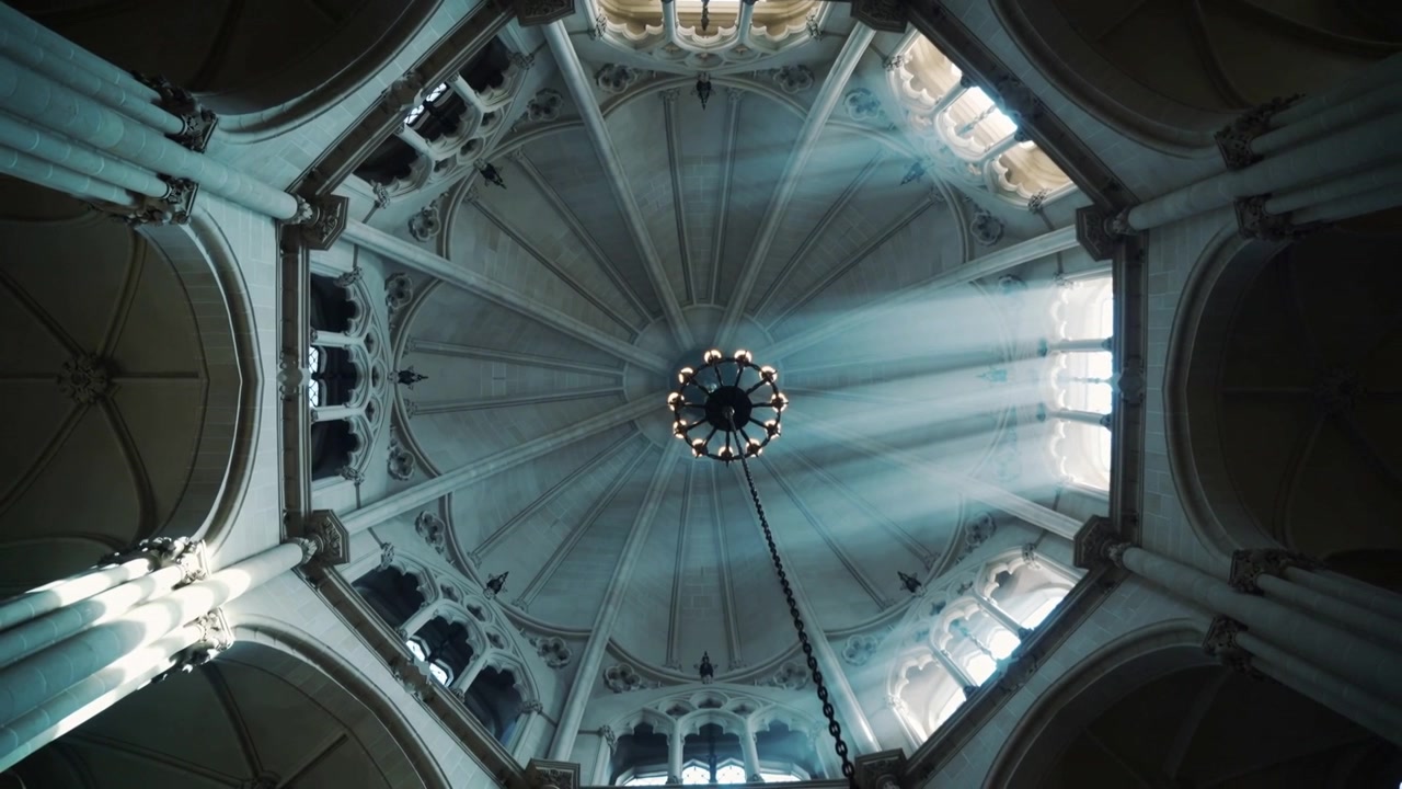 Raggi di sole che filtrano attraverso finestre a cleristorio, spostandosi sulla cupola e sulla catena del lampadario all'interno di una chiesa.