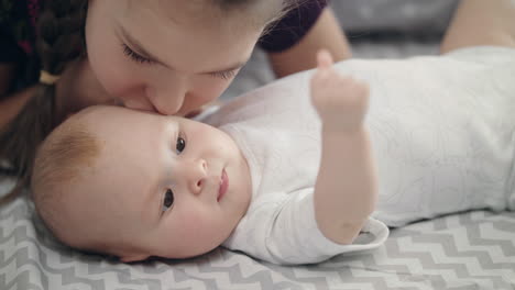 sister kiss adorable baby brother. close up of girl lovely kiss baby boy face