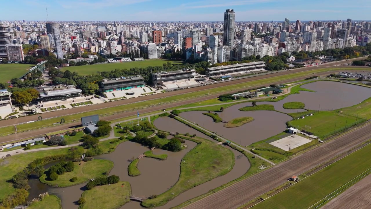 Vista aerea del complesso dell'autodromo con stagni e bandiera argentina vicino allo skyline della città.