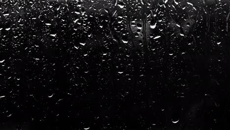 drops on glass on a dark background. raindrops from the copy space. rain outside the window black background