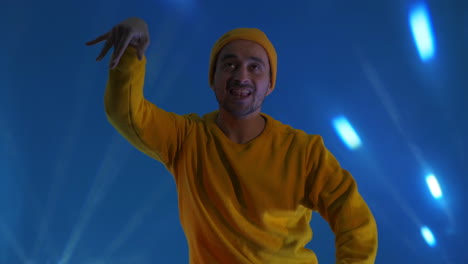 smiling man dancing in studio. joyful guy gesturing with hands. man having fun. man smiling and dancing challenge dance in good mood on blue background.unstoppable fun happiness comical portrait.