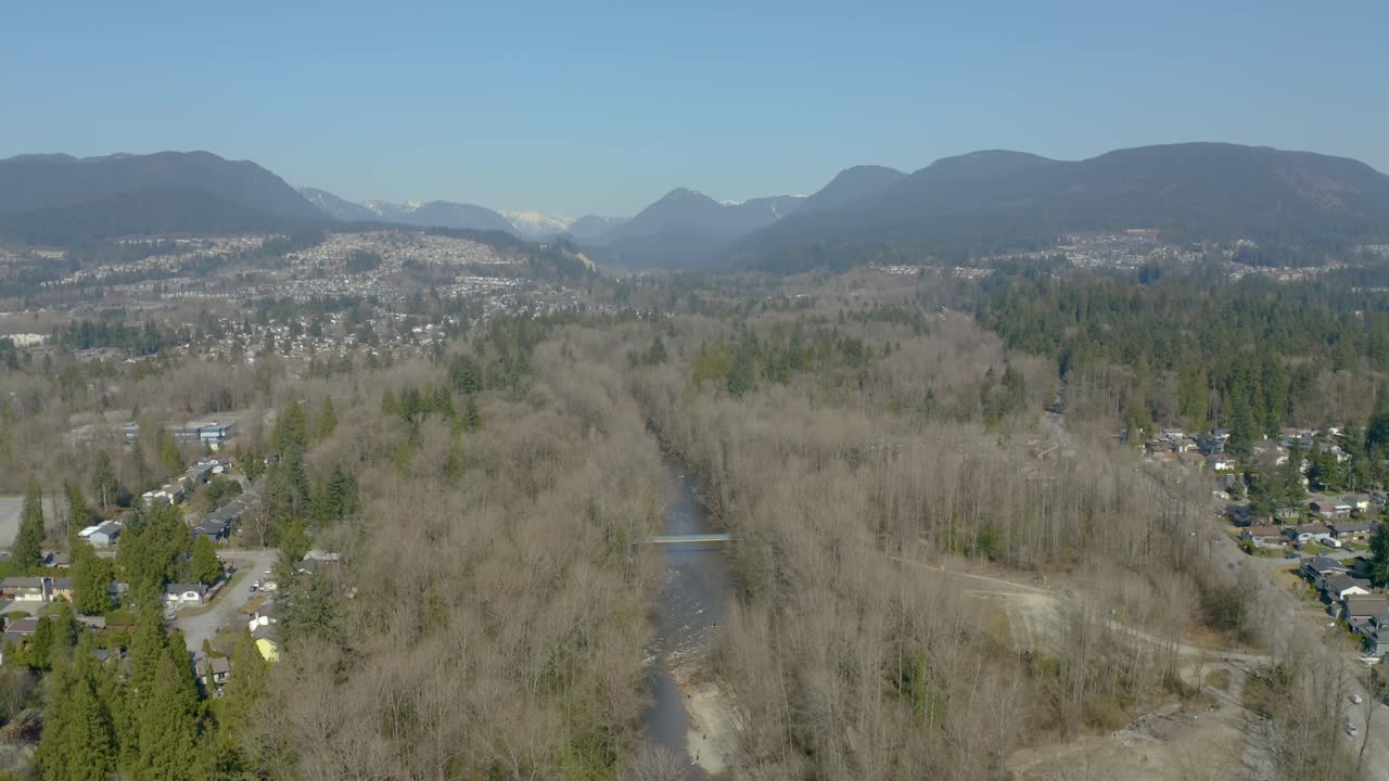 Suburban landscape with river and view of the mountains in the background. Above river bed.