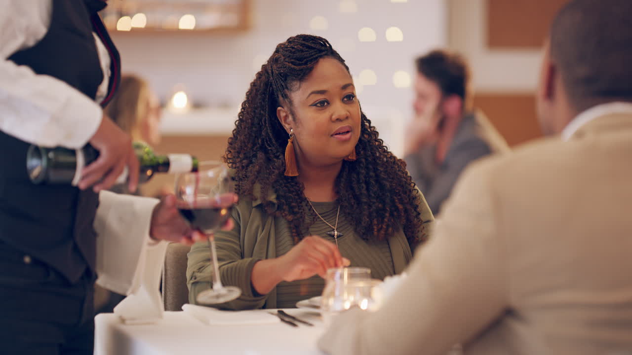 a waiter topping up a couple's wine glasses