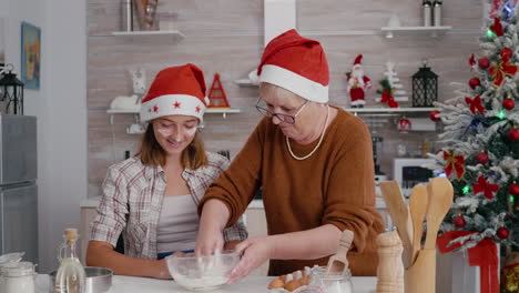 la abuela con la nieta mezclando ingredientes huevo con harina preparando masa tradicional casera