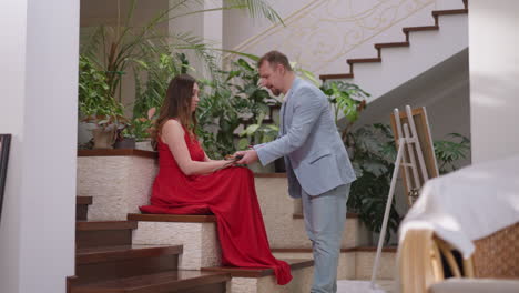 el artista muestra la postura al modelo en el estudio. el pintor cuidadoso arregla las manos de la mujer con una rosa para el retrato en el taller de arte. el hombre trabaja con la dama en el dibujo