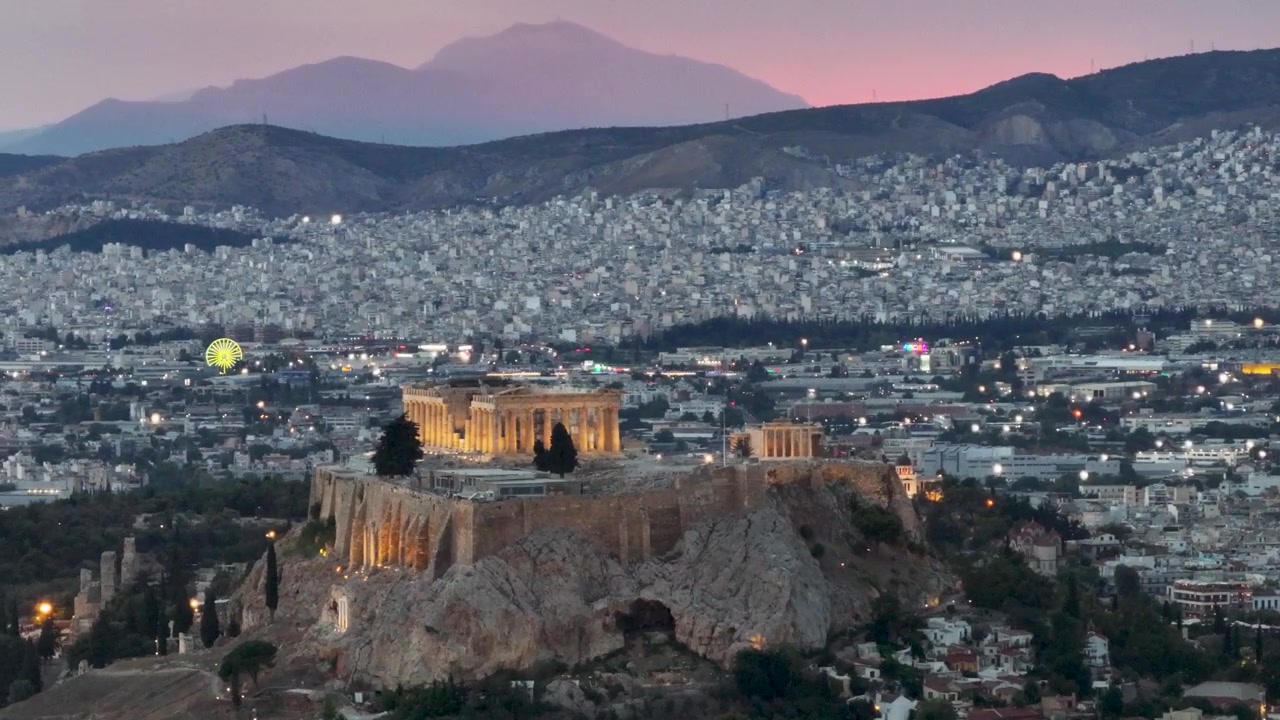 Collina dell'Acropoli e tempio del Partenone illuminati contro un cielo al tramonto rosa, che dominano le luci diffuse della città di Atene al crepuscolo in Grecia