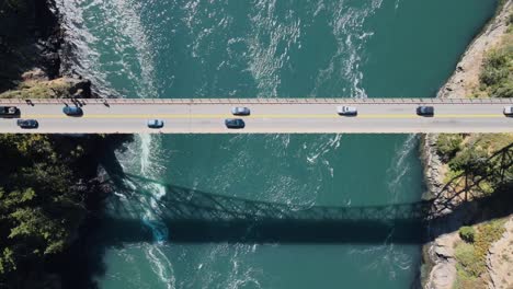 top-down shot of vehicles driving across deception pass with a river running