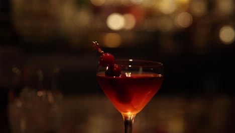a cocktail splashes in a glass against a bar backdrop.