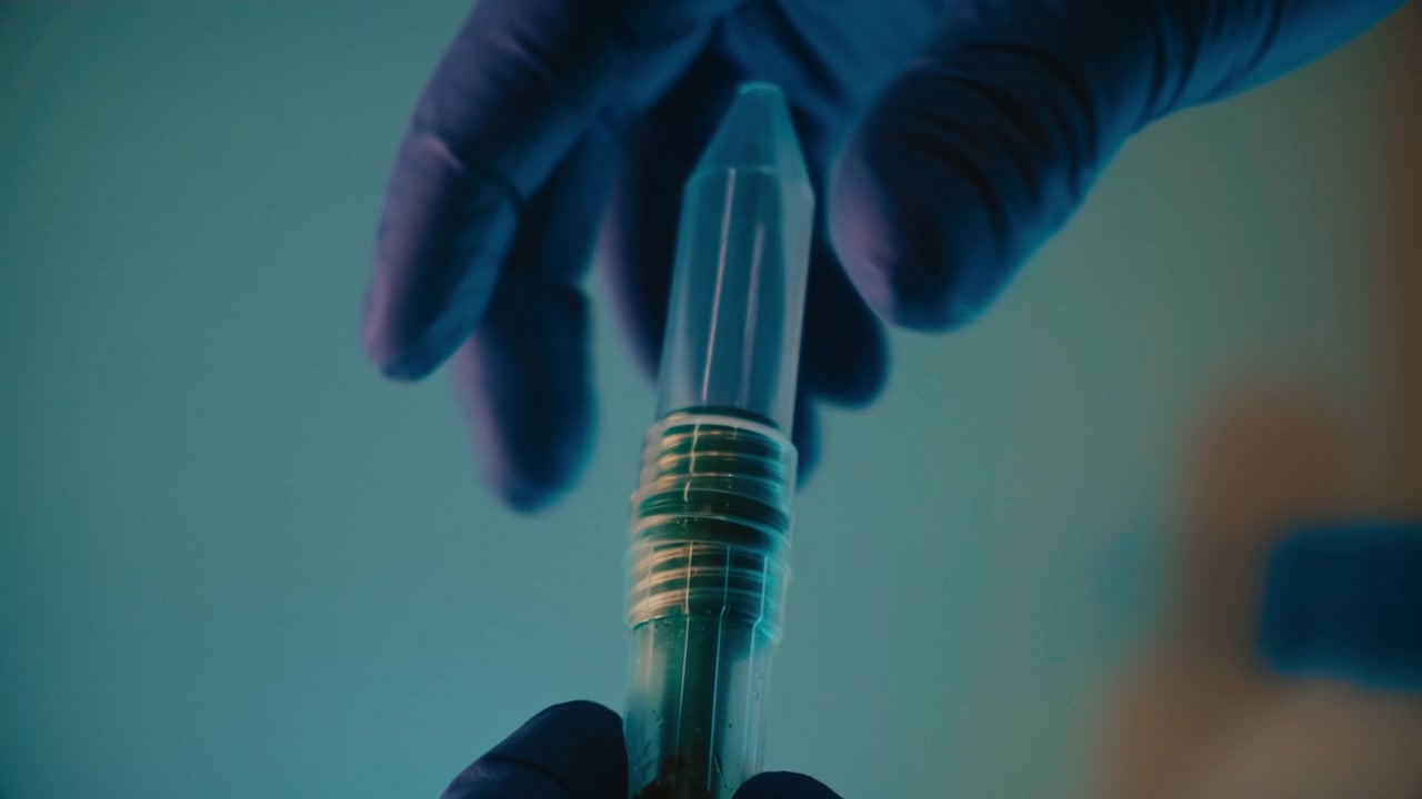 Hands closing a laboratory sample tube.