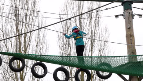 young girl walking across tyres on ropes on a high wire adventure obstacle course