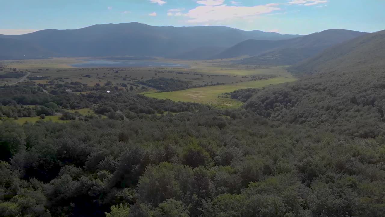 vista aérea girando y ascendiendo de un valle verde con agua en el medio