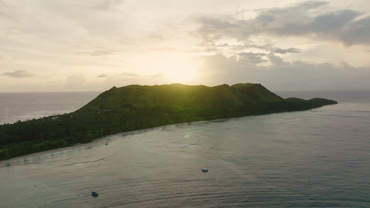 Island silhouette at dusk with warm sky and soft reflection on ocean surface