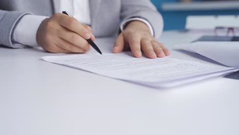 Concentrated-young-businessman-in-formal-suit-carefully-reads-contract-terms-and-signs-on-paper.