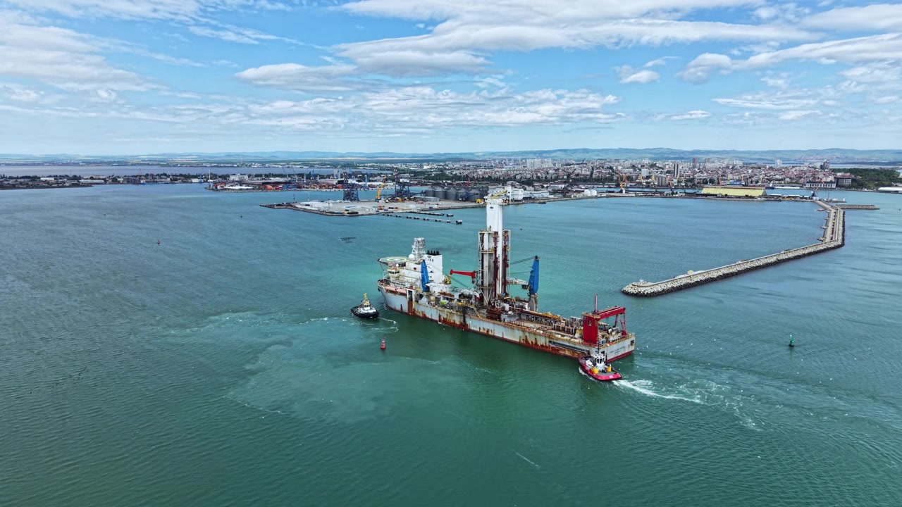 Industrial dredging vessel works in port area near city under clear sky with some clouds at daytime