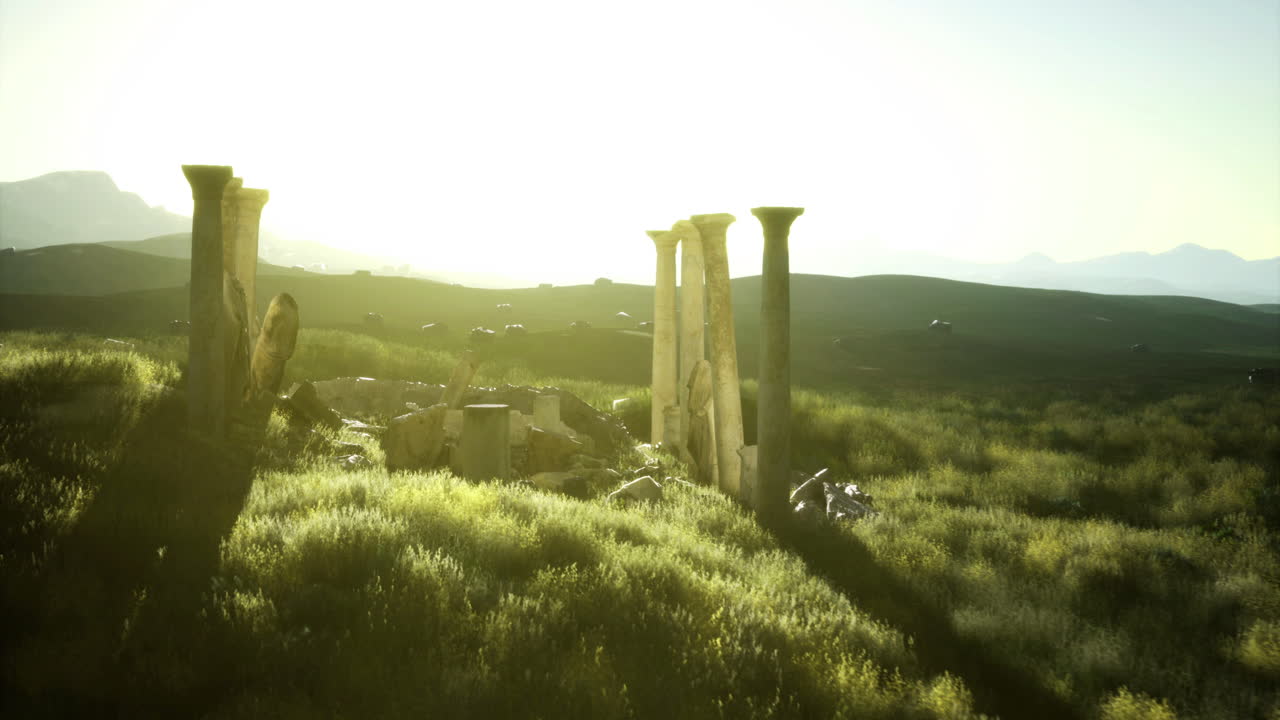 Ruins of ancient columns bathed in golden sunlight at dusk near mountains