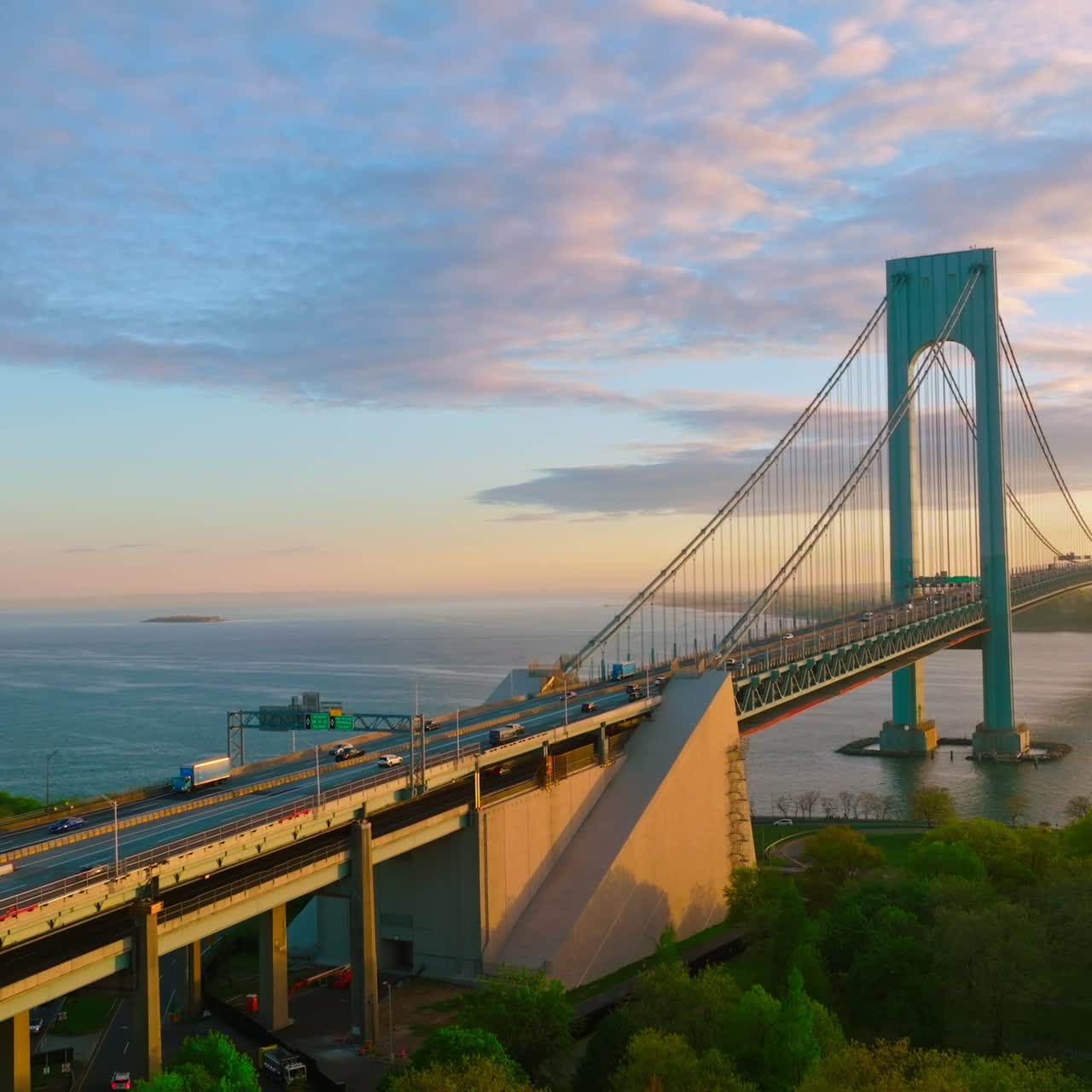 Quickly moving cars along the huge beautiful Bridge. Bronx-Whitestone Bridge crossing East River at the backdrop of amazing sky