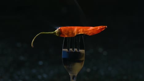 Closeup-shot-of-burning-hot-red-chilli-pepper,-steaming-sticked-to-fork