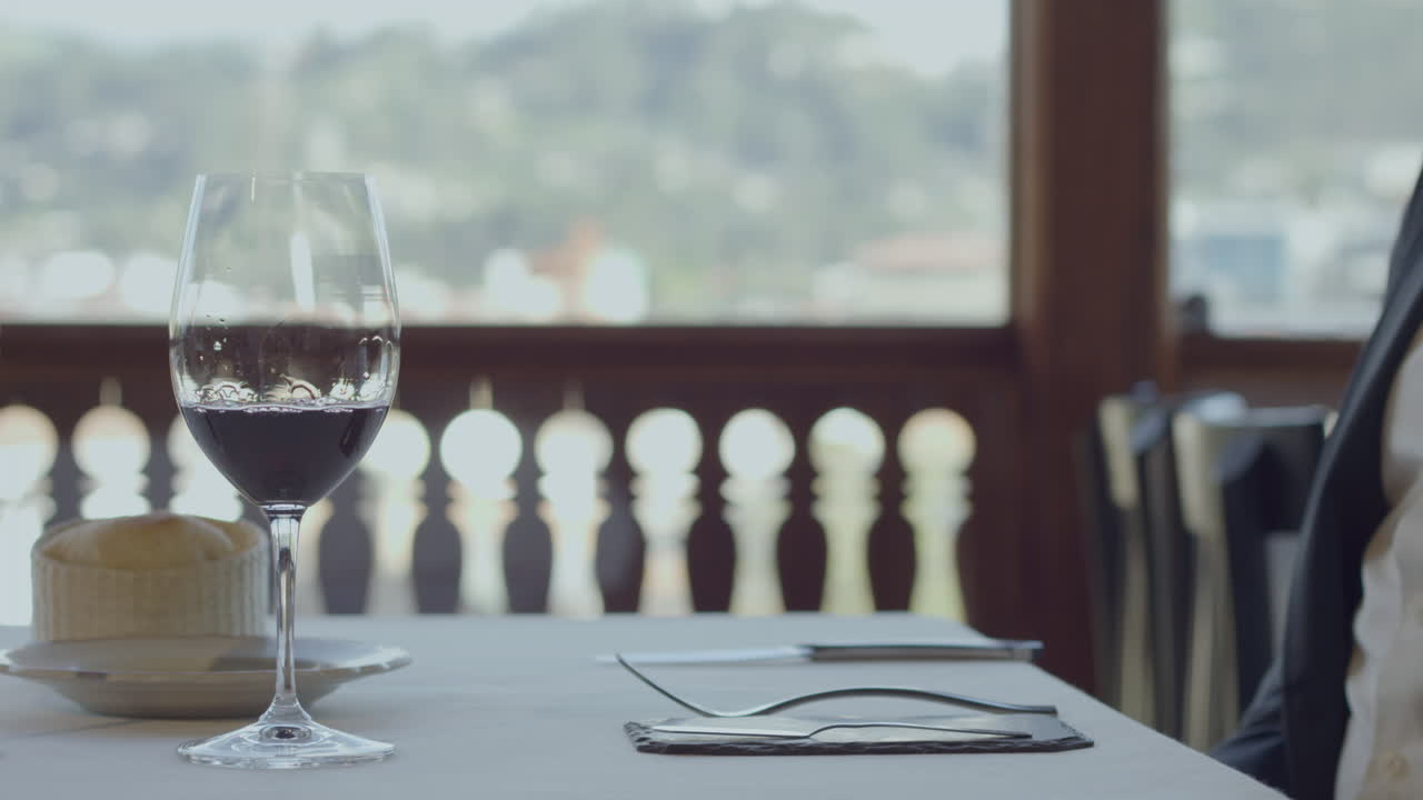 Close-up of a restaurant table with a glass of red wine, white tablecloth and neatly arranged cutlery