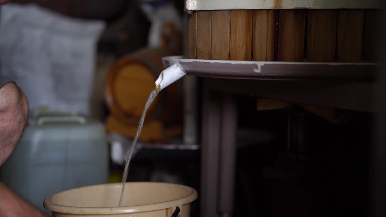 Older vintner using hydraulic wine press to squeeze all the juice out of harvested grapes