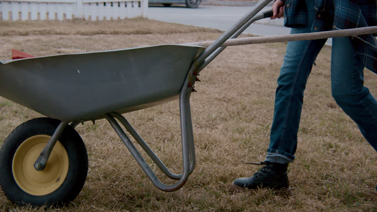 Person pushing a wheelbarrow in a yard