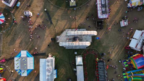 top down aerial of people at outdoor carnival enjoy fair rides