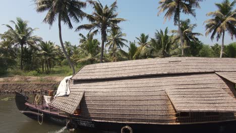 Orilla-Del-Río-Palmera-En-Alappuzha,-Casa-Flotante-De-Madera-Navegando-En-El-Canal