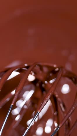 a whisk stirring melted chocolate smoothly