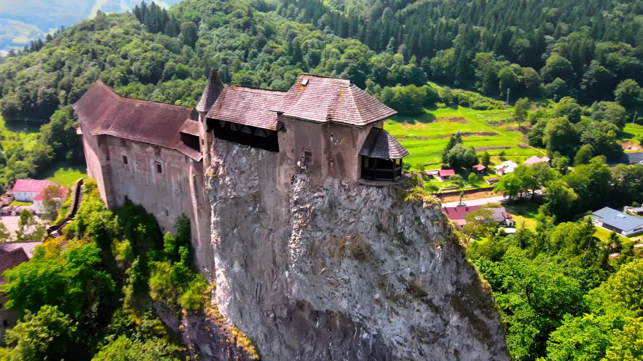 Letecký záběr středověkého Oravského hradu, jehož hradby a věže se tyčí na svislé vápencové skále na Slovensku.
